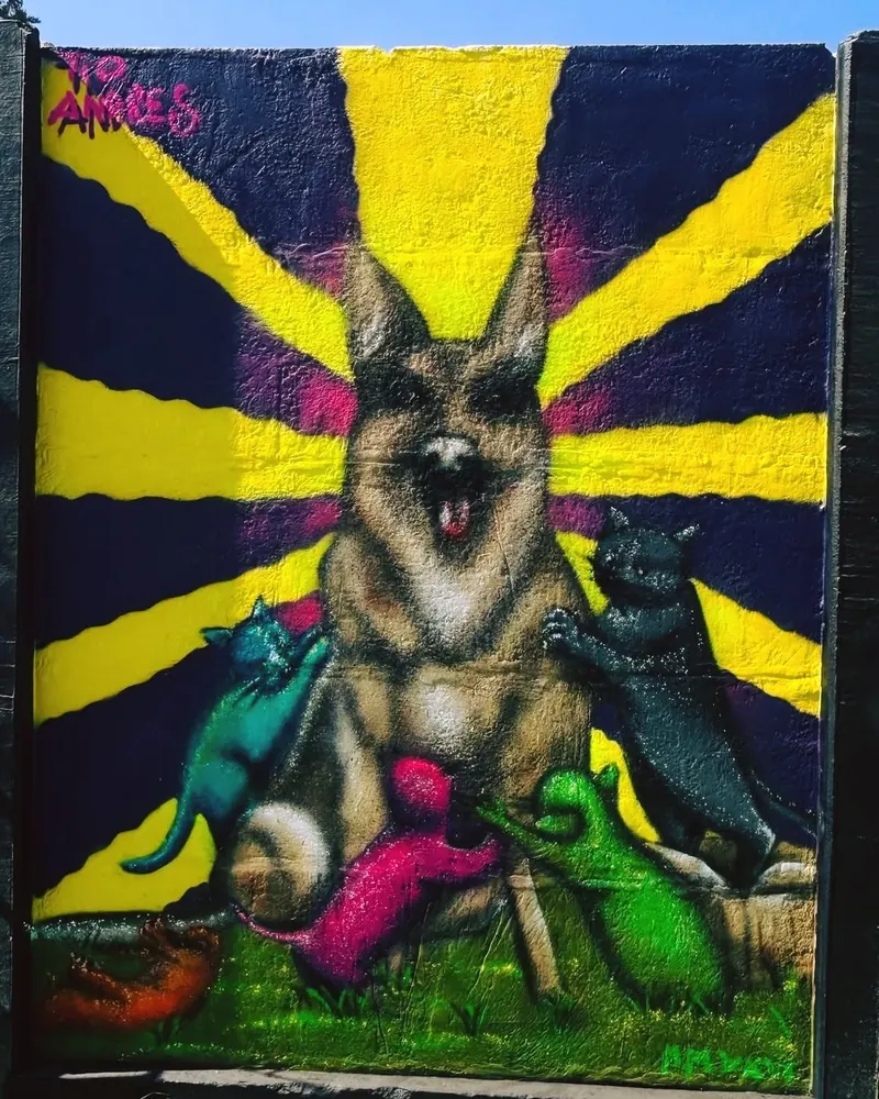 Mural colorido de un pastor alemán rodeado de gatos